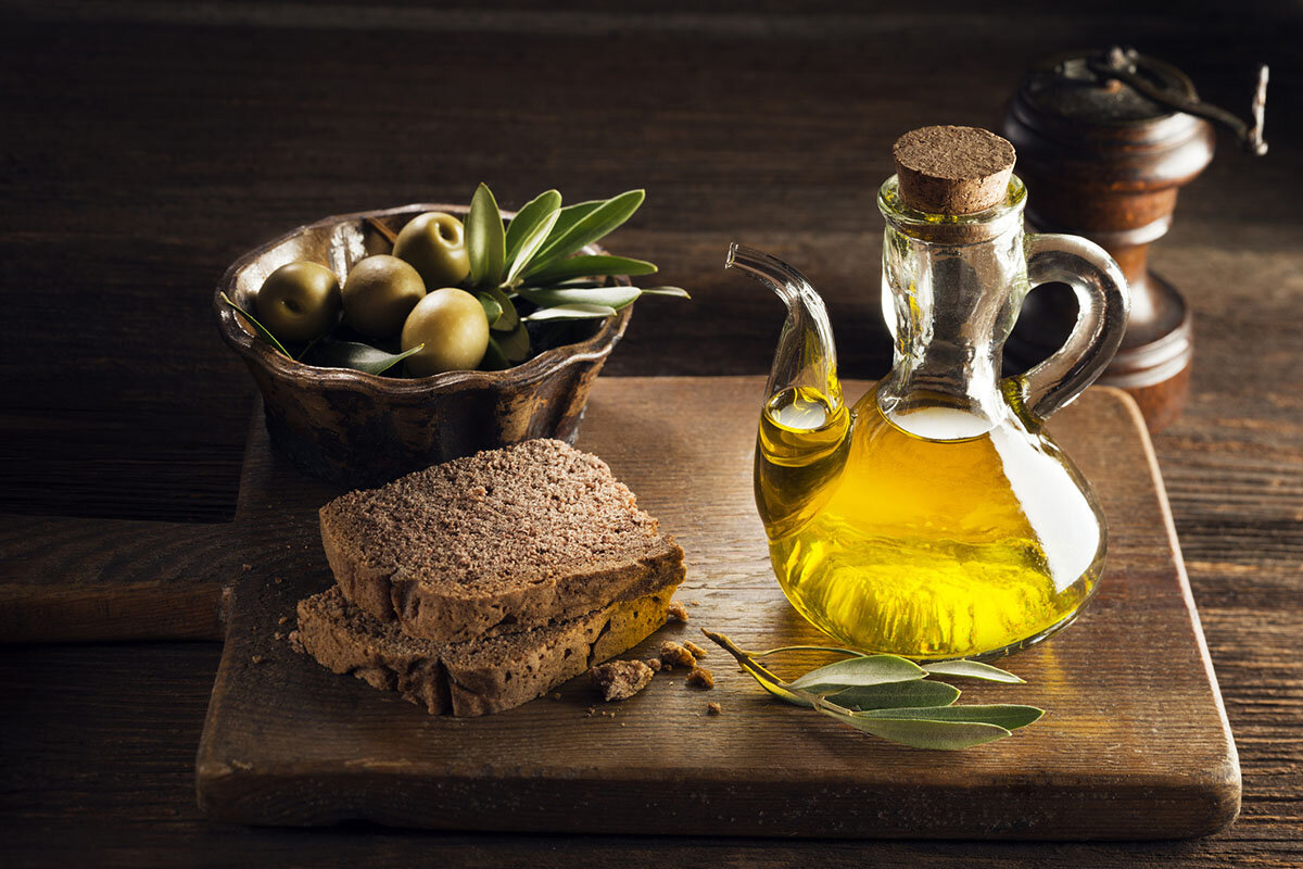 Eine Flasche Olivenöl und zwei Scheiben dunkles Brot