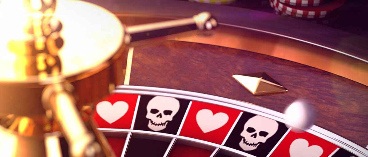 Ein Ausschnitt von eines Roulettetisches: Im Hintergrund stapeln sich Chips mit verschiedenen Werten, im Vordergrund sieht man das Rouletterad. Statt Zahlen tragen die roten Felder ein Herz-Symbol, die schwarzen einen Totenkopf.