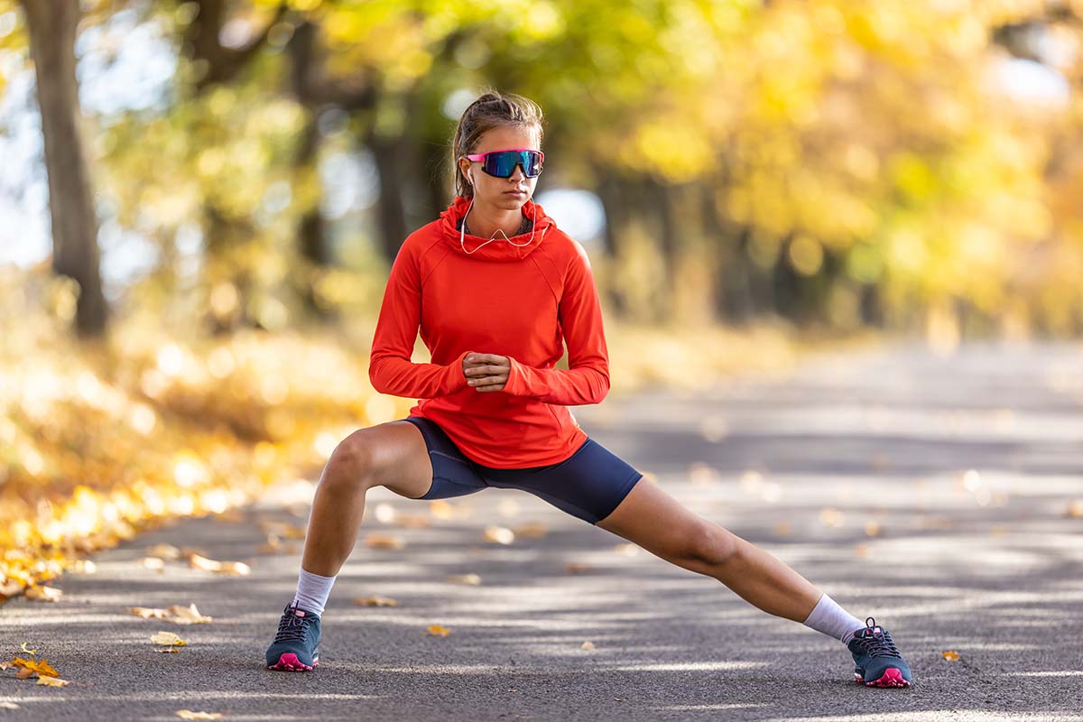 Eine Frau in Sportkleidung macht einen seitlichen Ausfallschritt, um die Innenseite der Oberschenkel zu dehnen.