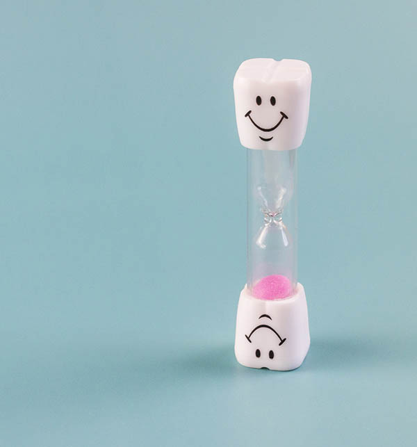Eine Sanduhr, ihre Enden sind in Form von Zähnen und haben Smileys.