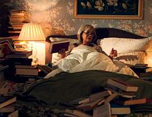 frau bei lampenlicht im bett mit vielen büchern.