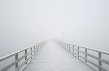 reifbedeckte holzbrücke im nebel