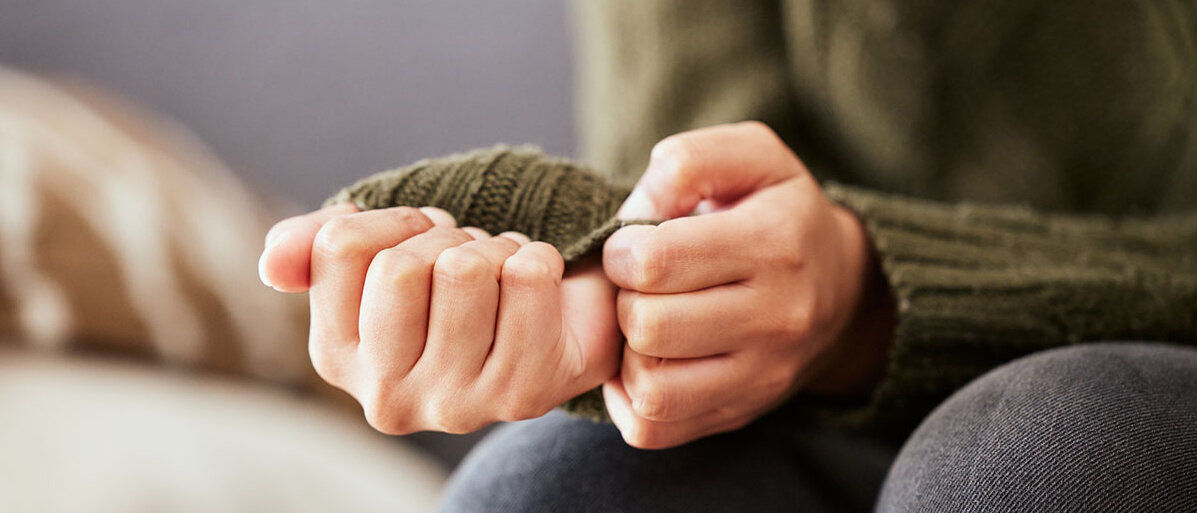 Angst vor Krebs Hände einer ängstlichen Frau auf einem Sofa