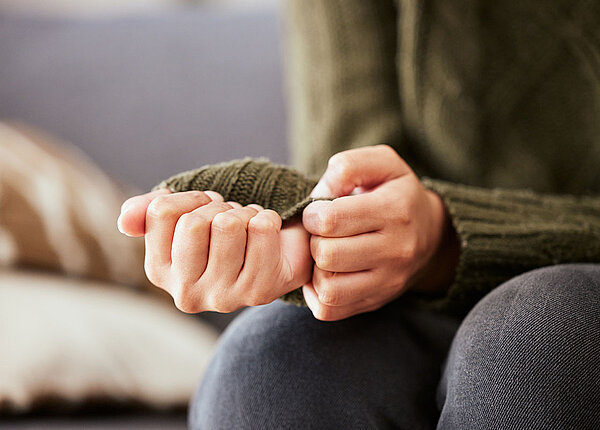 Angst vor Krebs Hände einer ängstlichen Frau auf einem Sofa