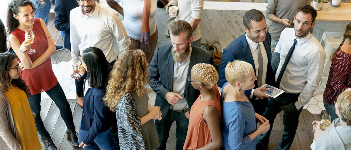 Aktives Zuhören durch Aufmerksamkeit oder Unachtsamkeit? So geht aufmerksam zuhören. Auf einer Stehparty haben sich viele Grüppchen gebildet und alle reden durcheinander.