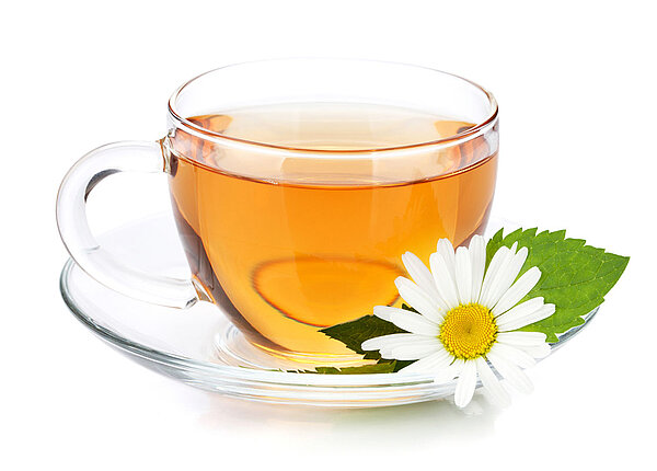 Tasse Tee mit Kamillenbluete an der Seite