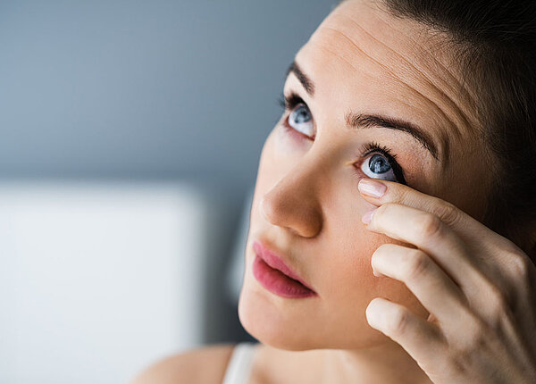 Worin sich ein Gersten- und ein Hagelkorn am Auge unterscheiden Frau hält vorsichtig ihren Finger ans Augenlid