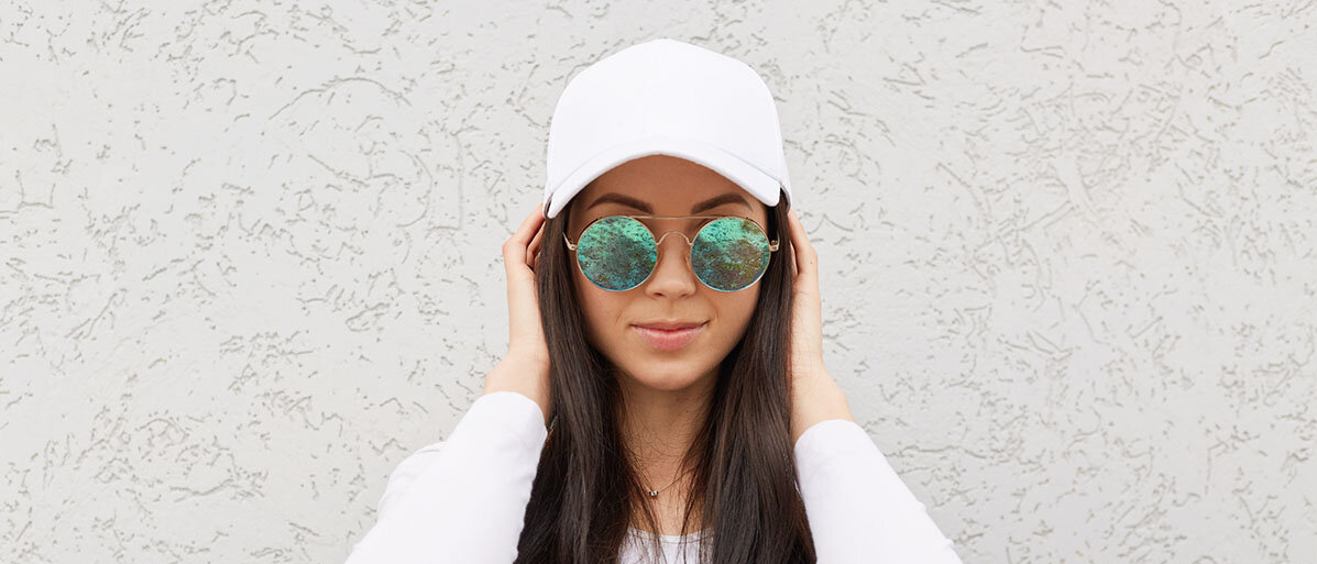 Frau trägt eine weiße Baseball Kappe und Sonnenbrille