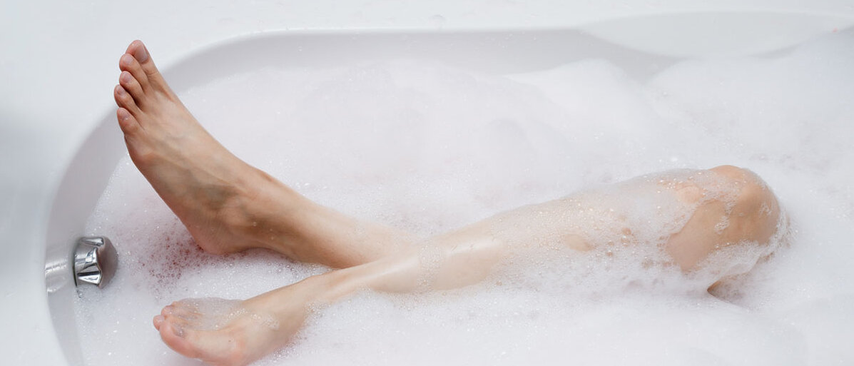 Baden bedeutet Wellness mit medizinischem Effekt Frauenbeine in einer Badewanne mit Schaumbad