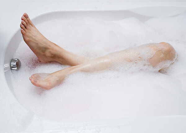 Baden bedeutet Wellness mit medizinischem Effekt Frauenbeine in einer Badewanne mit Schaumbad