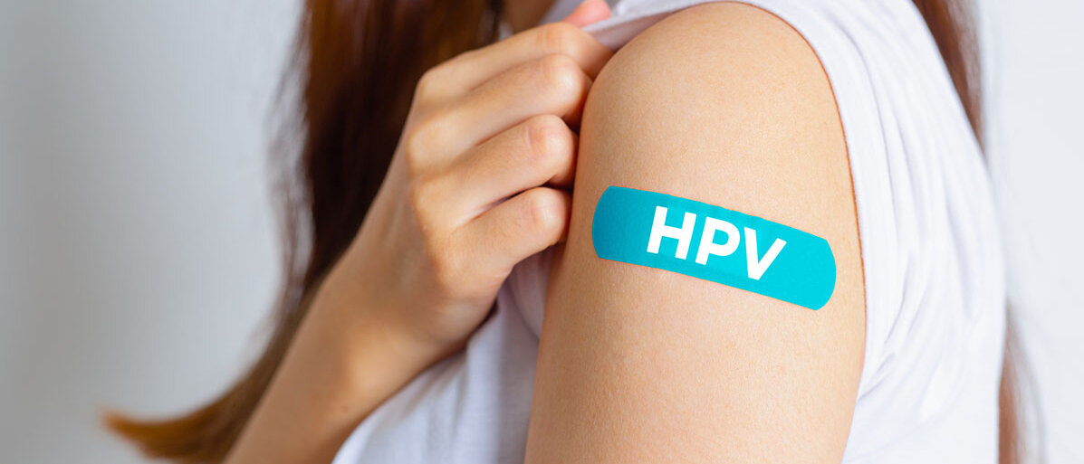 Junges Mädchen wurde gegen HPV geimpft und hat ein blaues Pflaster mit der Aufschrift HPV auf dem Arm