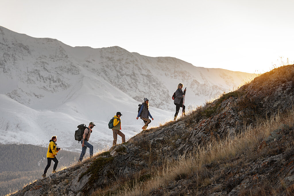 5 Personen in Trecking-Kleidung steigen hintereinander einen steilen Berg hinauf.
