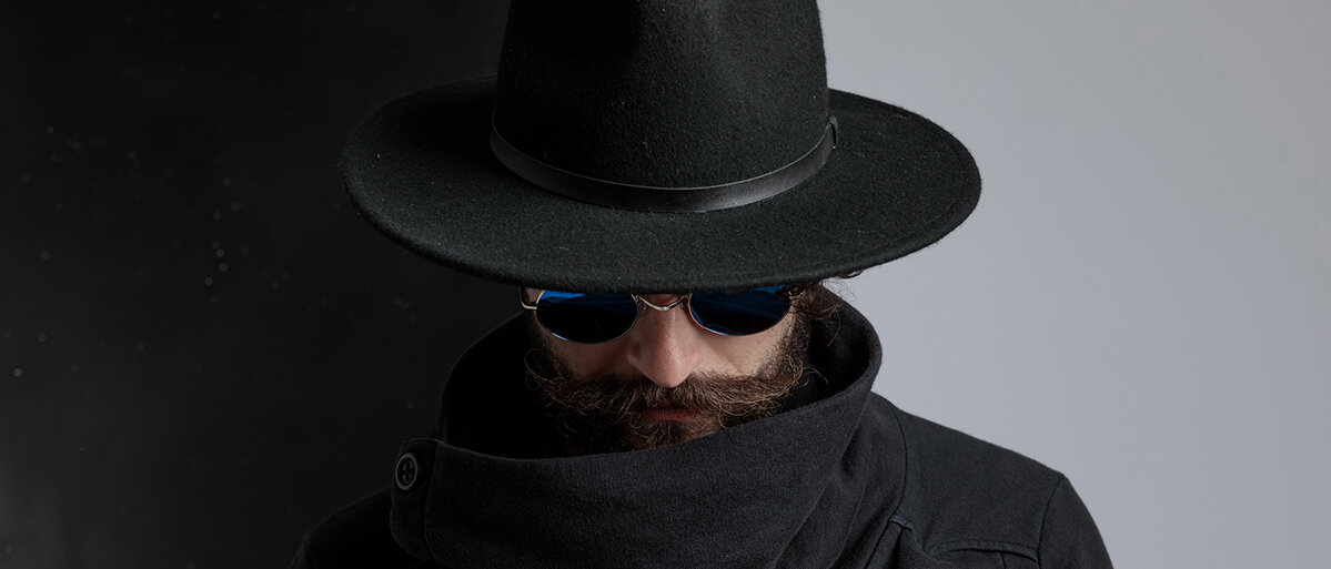 Mann mit Hut, schwarzen Mantel und Sonnenbrille