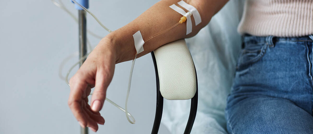 Eine Frau in einem bequemen Behandlungsstuhl bekommt eine Infusion in die Armvene.