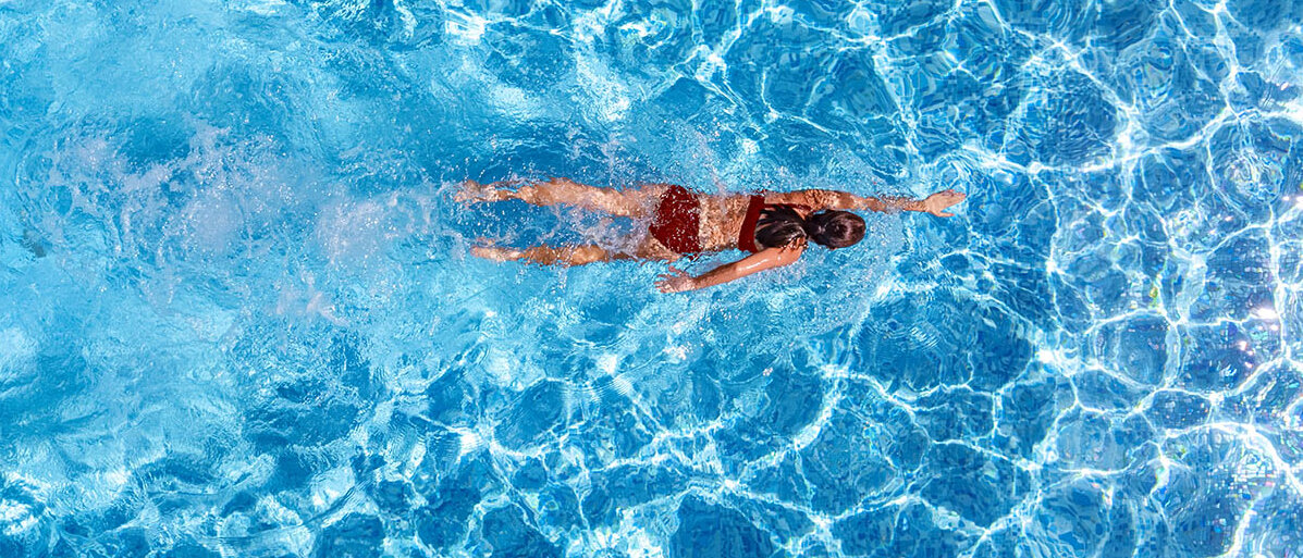 Eine Frau in rotem Bikini krault im Schwimmbad.