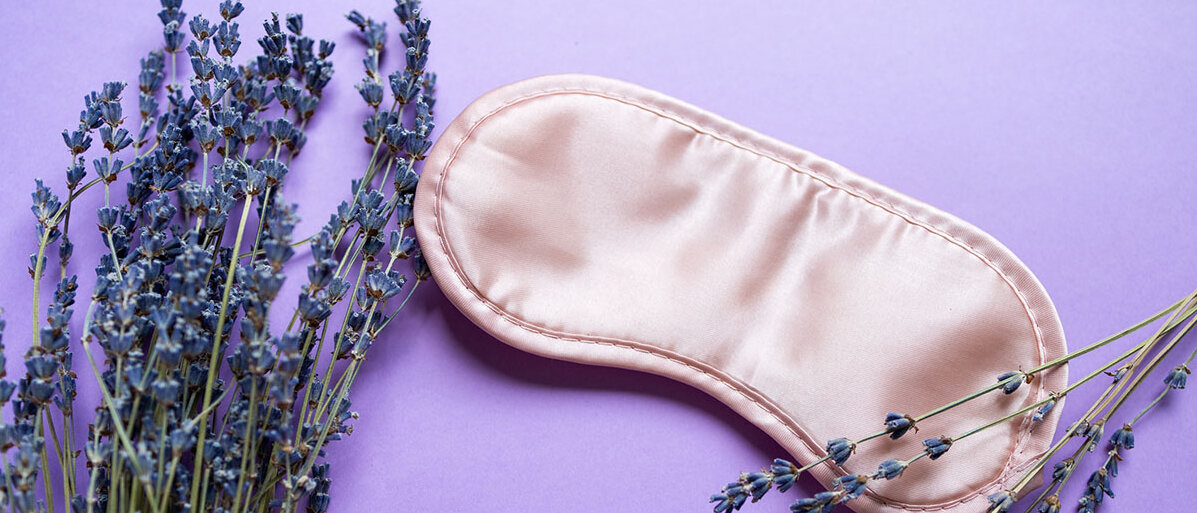 Entspannende Komposition mit Schlafmaske und Lavendelblüten