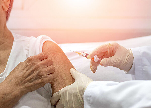 Seniorin bekommt Impfung in den Arm verabreicht