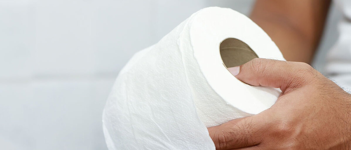 Neue Einteilung bei Harnwegsinfekten Nahaufnahme Man mit Klopapierrolle in der Hand