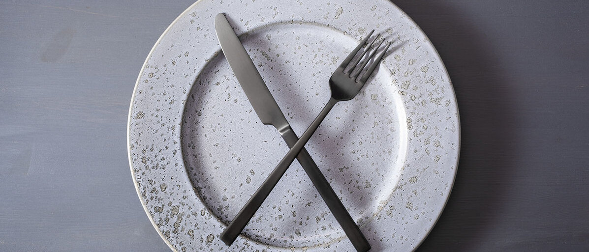 Diäten helfen nicht bei Adipositas. Ein leerer Teller, auf dem Messer und Gabel überkreuzt liegen.
