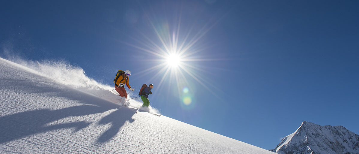 Zwei Skifahrer auf der Piste und die Sonne scheint