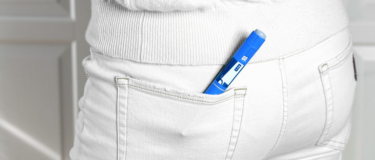 blaue Abnehmspritze in der hinteren Tasche einer weißen Jeanshose