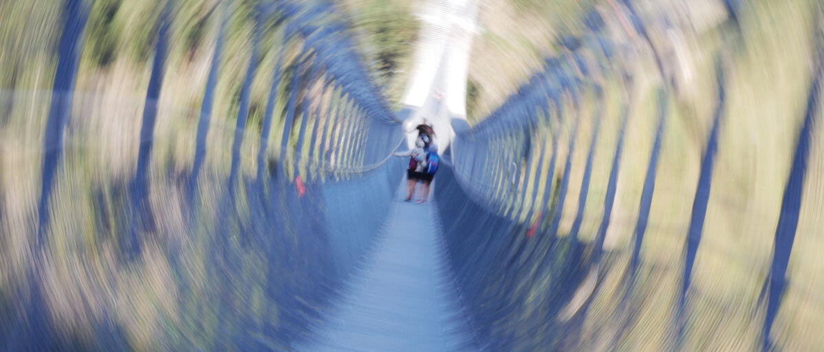 Reisen mit Phobien verschwommenes Bild von Menschen auf einer Hängebrücke