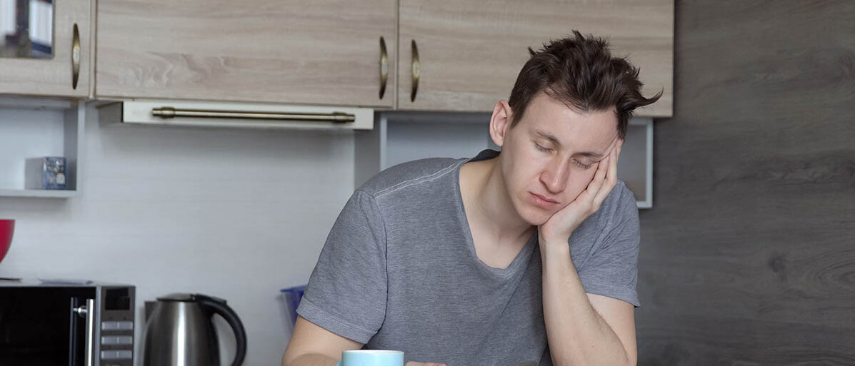 Ein Mann schläft am Frühstückstisch ein.