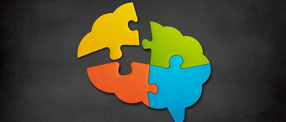 Gehirnförmiges bunte Puzzleteile auf schwarzem Hintergrund.