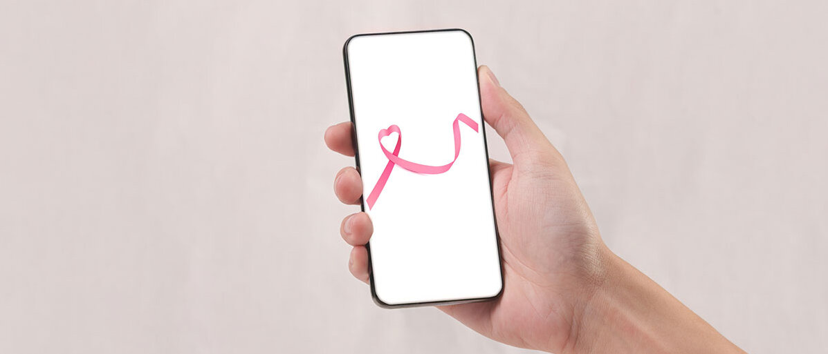 Brustkrebs-App ida care Frau hält Händy mit Brustkrebs-Schleife auf Display hoch