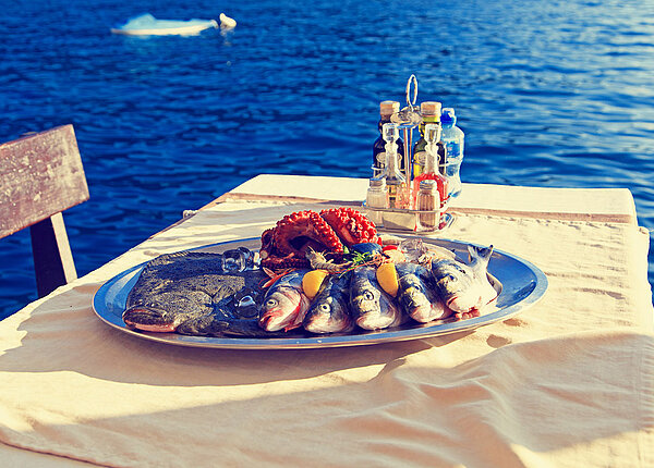 Teller mit Meeresfrüchten auf einem Tisch und im Hintergrund das Meer