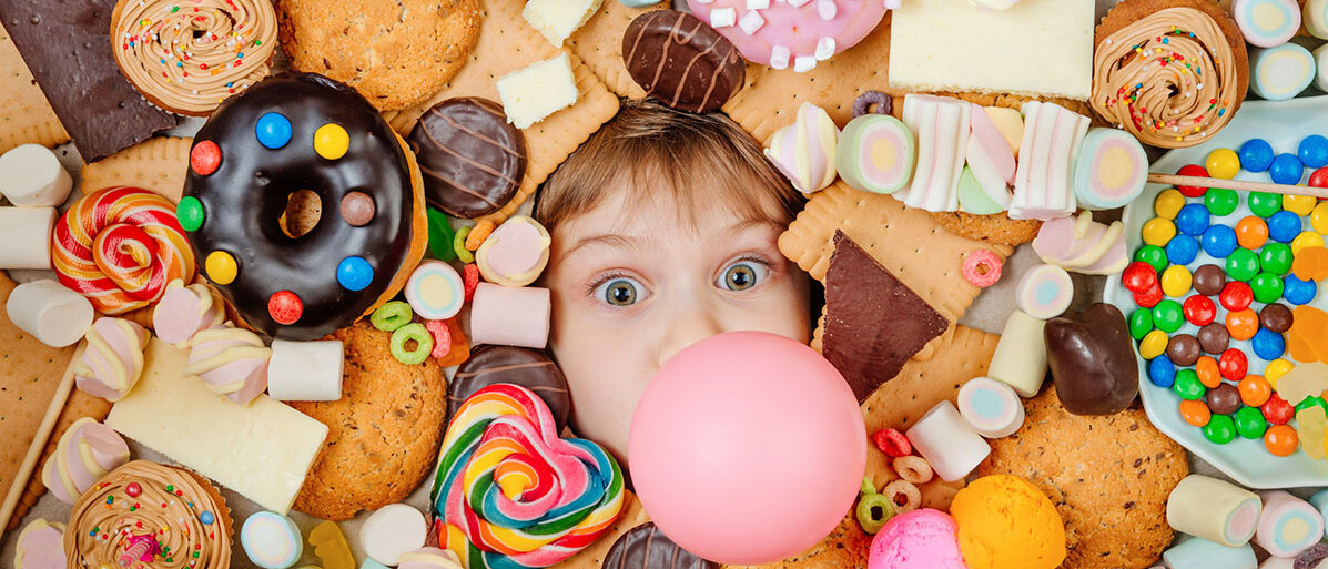 Kind schaut zwischen lauter Süßigkeiten mit seinem Kopf hervor