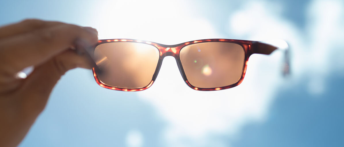 Mann hält Sonnenbrille in die Luft