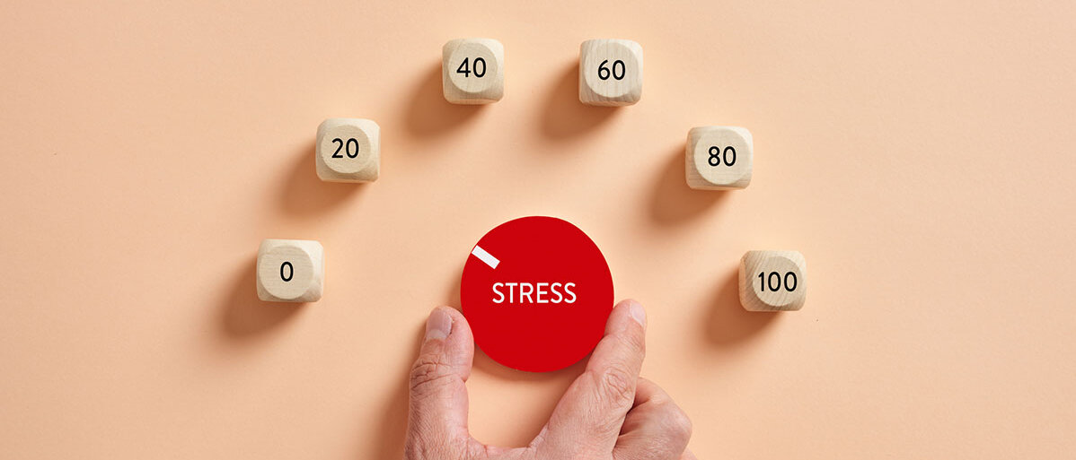 Ein Drehregler, der den Stresspegel in 20er-Schritten bis 100 anzeigt: Eine Hand dreht daran.