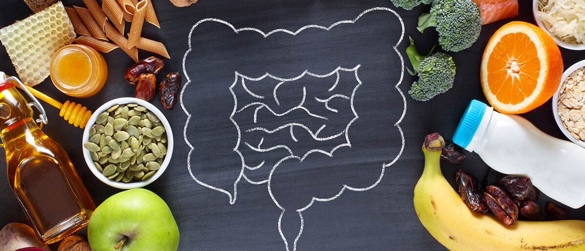 Ballaststoffreiche Lebensmittel Kreidezeichnung eines Darms auf einer schwarzen Schiefertafel, darum verteilt ballaststoffreiche Lebensmittel