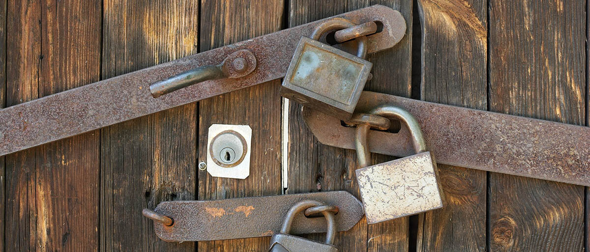 Ein Holztor ist mit fünf Schlössern gesichert.