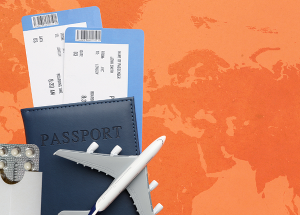 Pillen-Blister, Flugtickets, Pass und Miniaturflugzeug auf orangefarbenem Hintergrund mit Weltkarte 