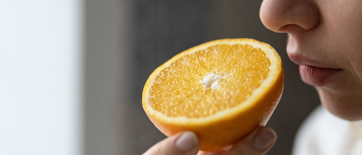 Frau riecht an einer aufgeschnittenen Orange