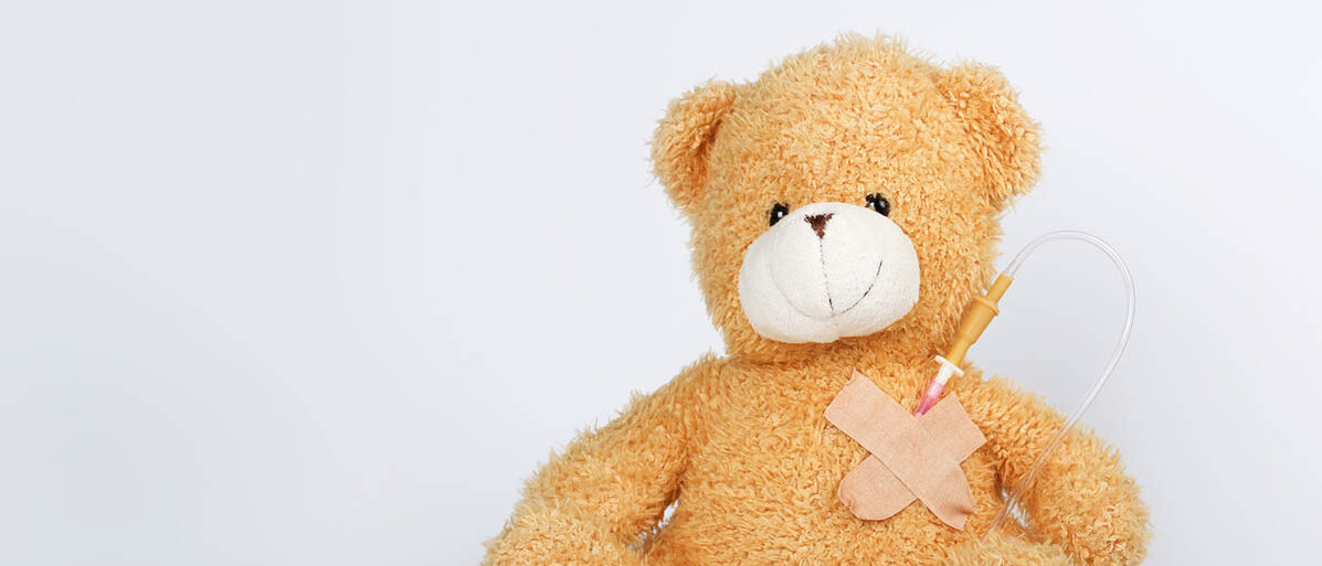 Ein Teddybär hat einen Venenzugang an der Brust.
