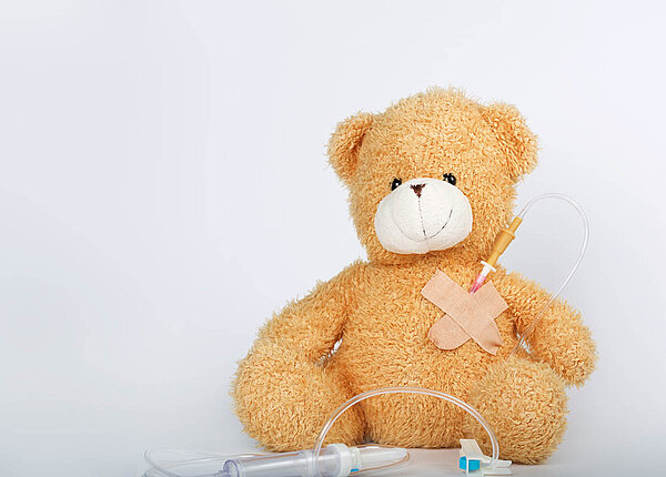 Ein Teddybär hat einen Venenzugang an der Brust.