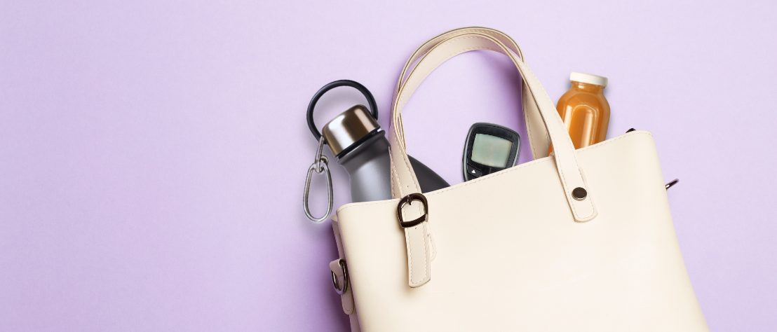 Aus einer Handtasche schauen eine Wasserflasche, eine Saftflasche und ein Blutzucker-Messgerät heraus.