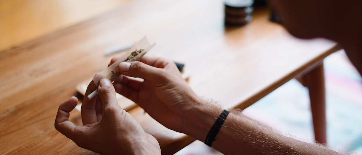 Mann, der einen Joint mit Cannabis dreht 