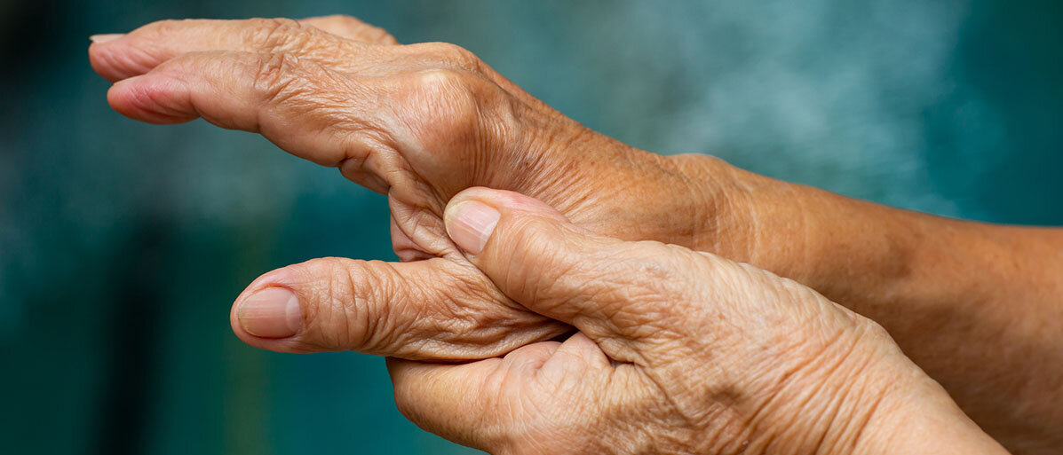 Hände einer älteren Frau. Sie hält mit einer Hand den Daumen der anderen Hand