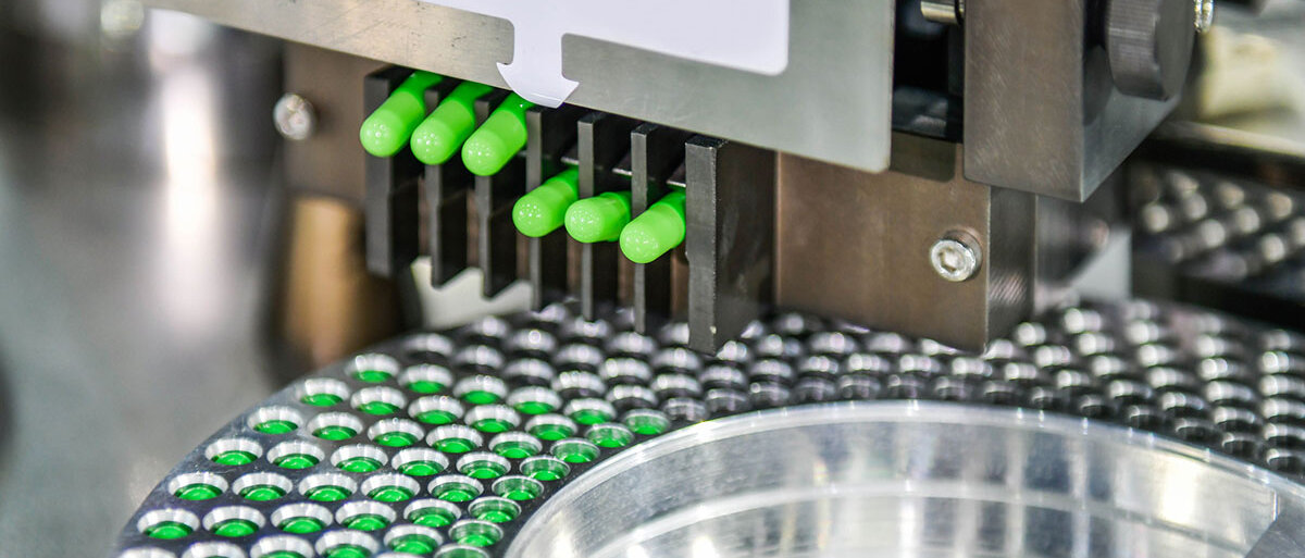 Eine Anlage aus Edelstahl befüllt zahlreiche Neongrüne Kapseln.