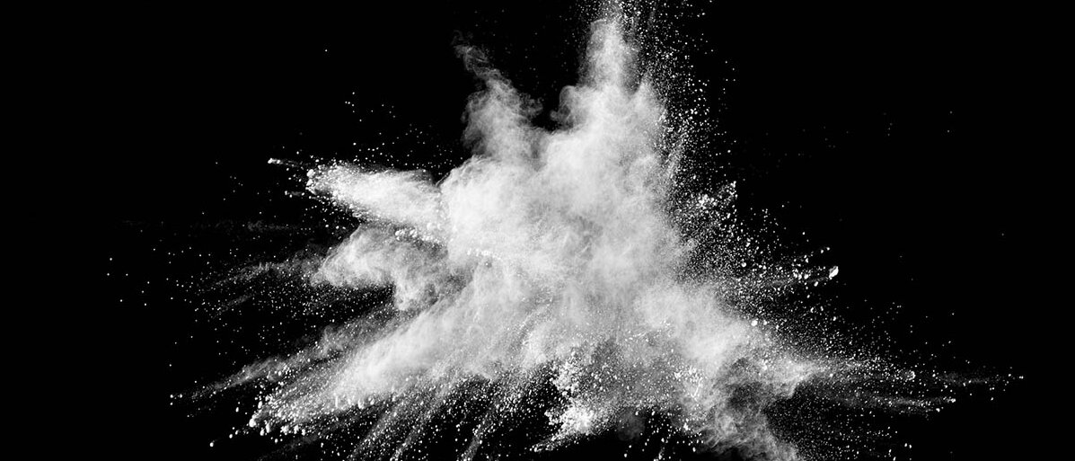 Weißes Pulver explodiert vor schwarzem Hintergrund