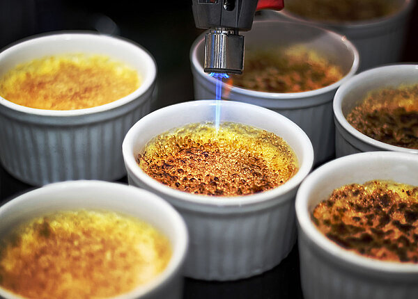Crème brûlée wird mit Bunsenbrenner flambiert