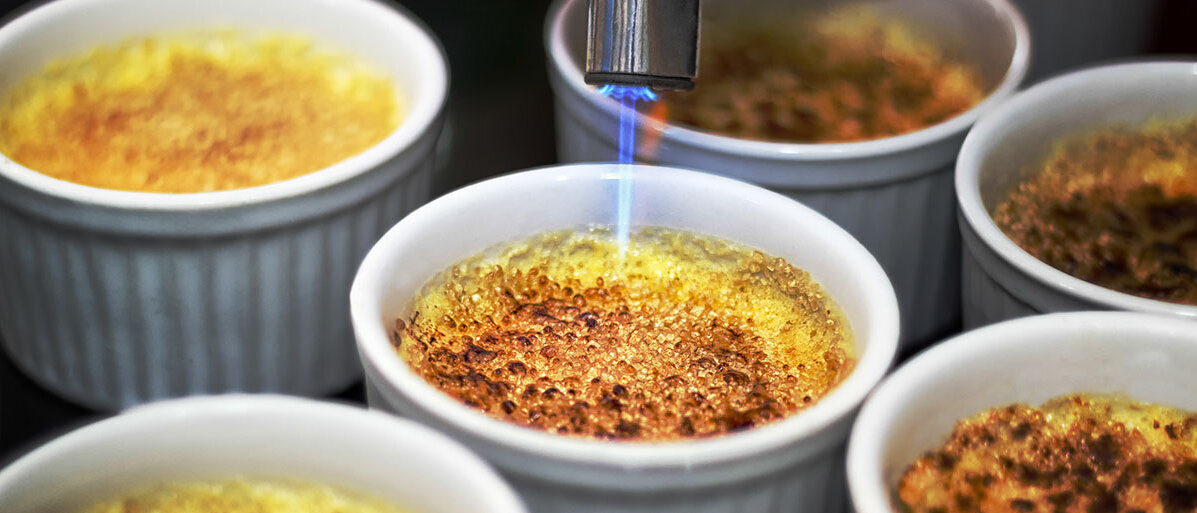 Crème brûlée wird mit Bunsenbrenner flambiert