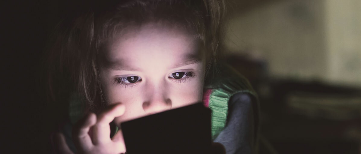 Mädchen sitzt im dunkeln vor einem Tablett