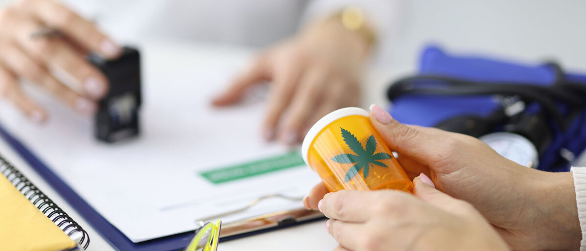 Nahaufnahme: Ärztin stellt Patientin Rezept für Cannabis aus und händigt ihr Röhrchen mit Cannabis aus. 