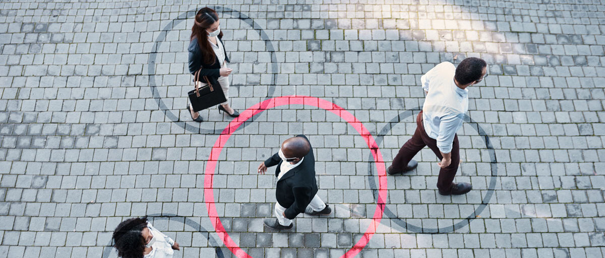 Fünf Menschen gehen über eine gepflasterte Straße. Um vier von ihnen ist ein grauer Kreis illustriert. Der Kreis um die Person in der Mitte ist rot und überschneidet sich mit den grauen Kreisen zweier anderer Personen.