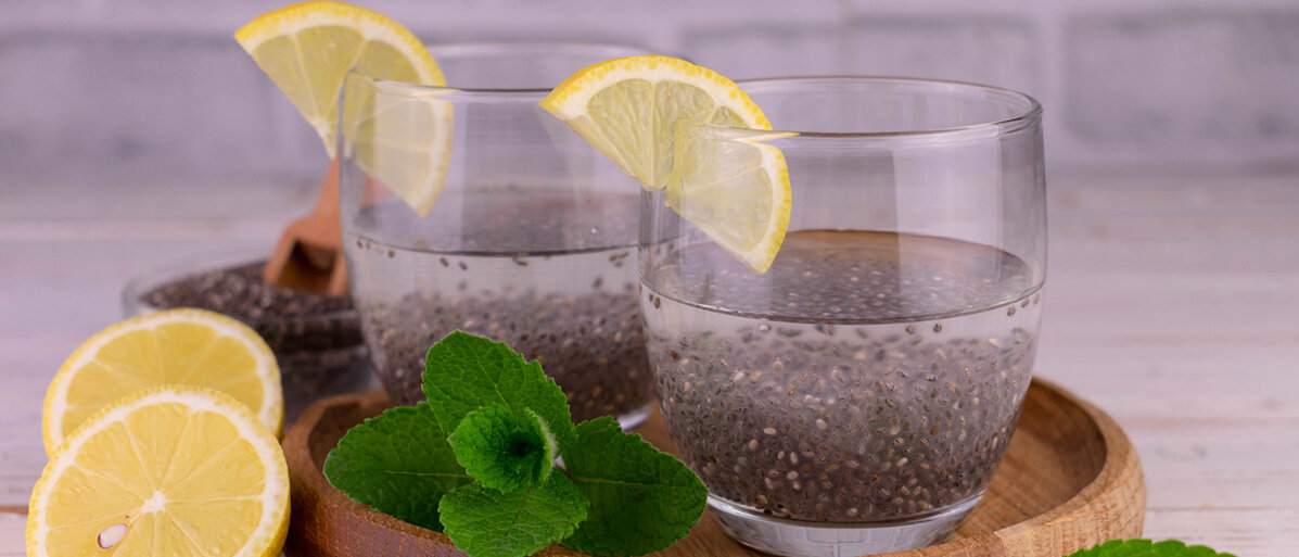 Zwei Gläser mit in Wasser aufgequellten Chiasamen, dekoriert mit Zitrone auf einem Tablett